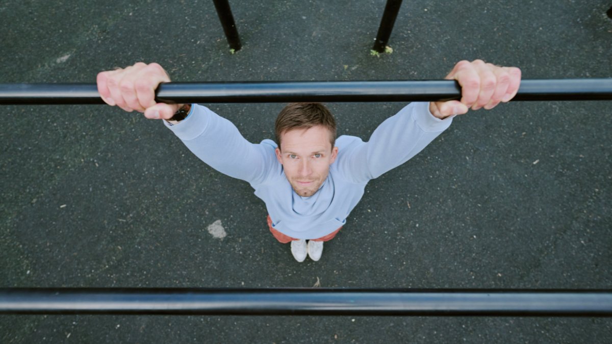 Calisthenics a Monza — atleta alle parallele vista dall'alto, allenamento outdoor a corpo libero